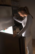 Woman opening fridge at night.