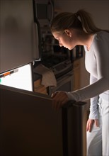 Woman opening fridge at night.