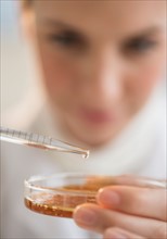 Close-up of scientist using pipette and petri dish.