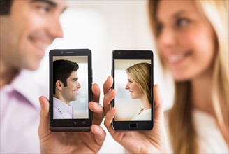 Couple holding smartphones with their pictures on.
