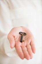 Female hand holding heart-shaped key.