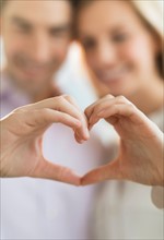 Couple making heart shape with hands.