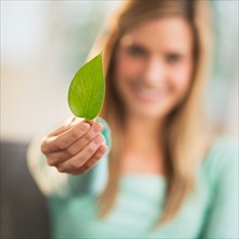 Woman holding leaf, focus on foreground.