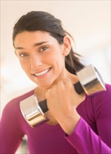 Young woman lifting dumbbell.