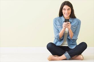 Woman sitting on floor and using cell phone.