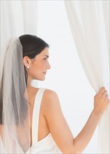 Bride looking through window.