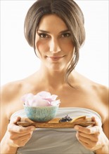 Woman holding tray with scented flower.