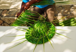 Man making hut with palm leaves. Jamaica.