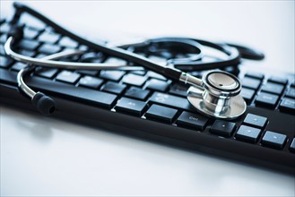 Close up of computer keyboard and stethoscope, studio shot.