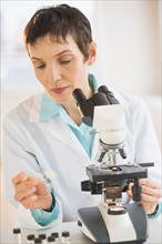 Woman working with microscope in laboratory.