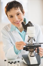 Portrait of smiling woman working with microscope in laboratory.