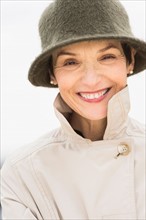 Portrait of smiling woman wearing raincoat and hat.