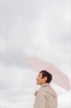 Woman wearing raincoat and holding umbrella.
