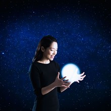 Woman catching glowing ball, studio shot.
