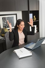 Businesswoman expressing happiness at desk.