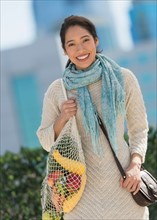 Portrait of smiling young woman with grocery shopping bag.