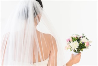Portrait of bride in veil holding bouquet.