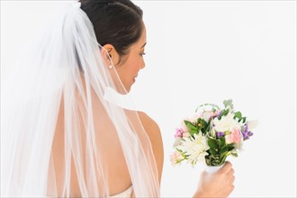 Portrait of bride in veil holding bouquet.