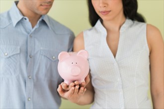 Young couple holding piggy bank.