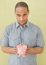 Young man holding piggy bank.