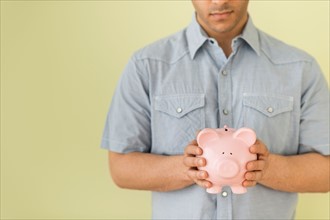 Young man holding piggy bank.