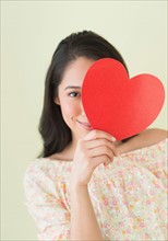 Young woman holding red paper heart.