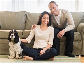 Young couple with dog in living room.