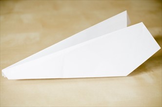 Paper plane on wooden surface