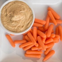 Young carrots and hummus in bowl