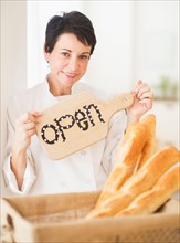 Portrait of mature woman holding basket with baguettes