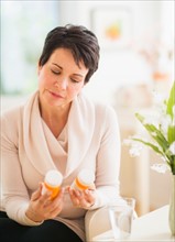 Portrait of mature woman looking at pill bottles