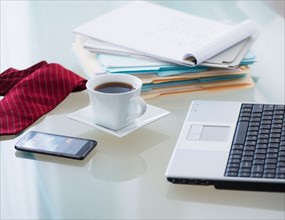Close-up of coffee, paper material , tie, mobile phone and laptop