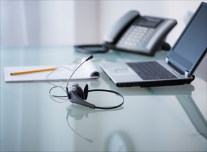 View of headset, telephone, laptop and paper material on desk