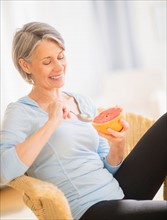 Portrait of woman eating grapefruit