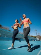 Two women running at sports field