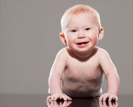 Studio shot of naked baby boy (18-23 months) crawling