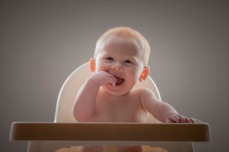 Studio shot portrait of naked baby boy (18-23 months) with finger in mouth