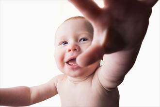 Studio shot of baby boy (18-23 months) reaching camera