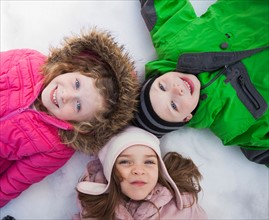 Directly above portrait of three children (2-3, 4-5) lying on snow