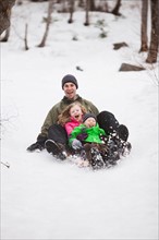 Portrait of young man sledding with children (4-5)