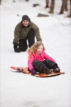 Young man sledding with girl (4-5)