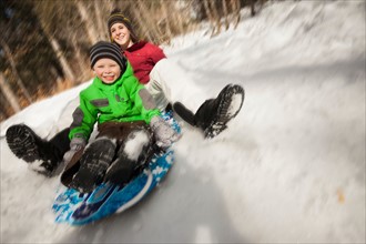 Young woman sledding with boy (4-5)