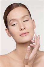 Studio shot of young woman applying moisturizer on face