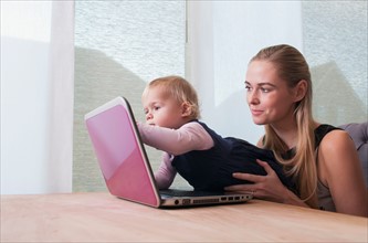Baby girl (12-17 months) and mother using laptop