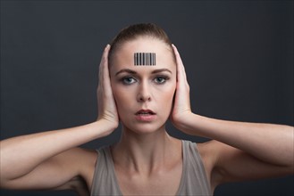 Studio portrait of woman with bar code on forehead