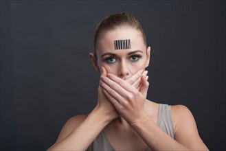 Studio shot of young woman covering her mouth