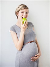 Studio Shot of pregnant woman eating apple