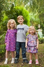 Brother (6-7) and sisters (2-3,4-5) posing together in garden
