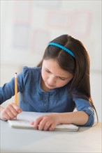Schoolgirl (8-9) writing in notebook.