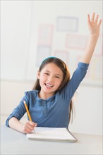 Portrait of schoolgirl (8-9) raising hand.